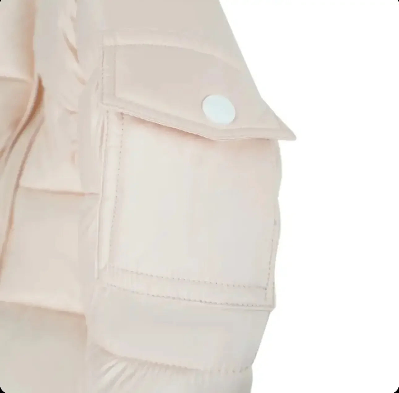 Close-up of beige puffer jacket sleeve with flap pocket and white snap button detail