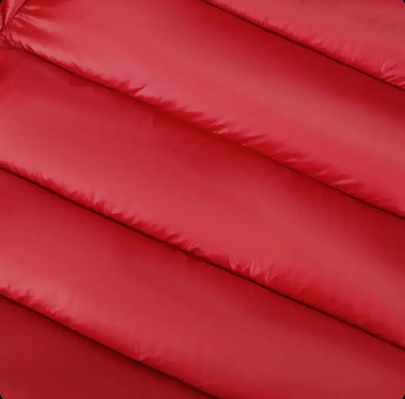 Close-up of red quilted fabric with horizontal padded stitching, showing texture and seams