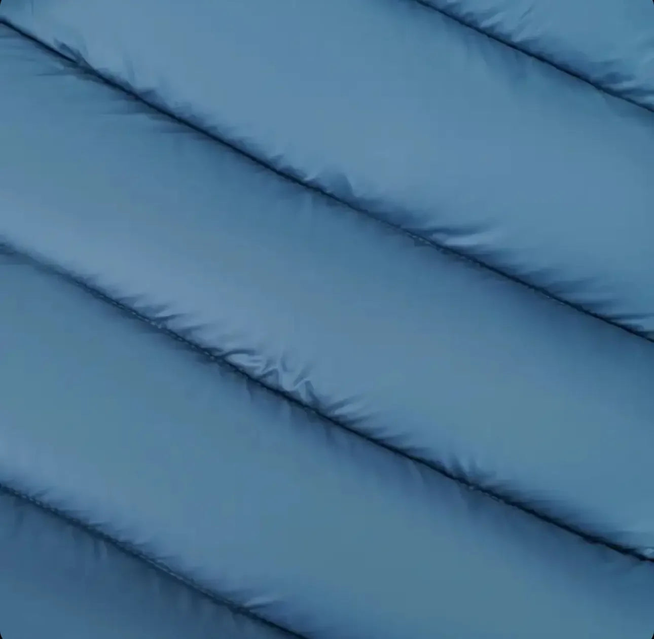 Close-up of blue quilted fabric, puffer jacket material with horizontal stitching