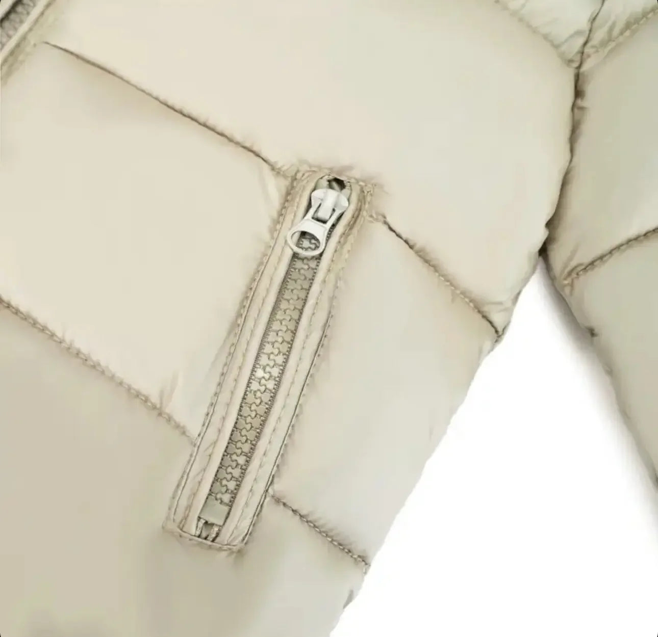 Close-up of beige quilted jacket sleeve with zipper pocket detail