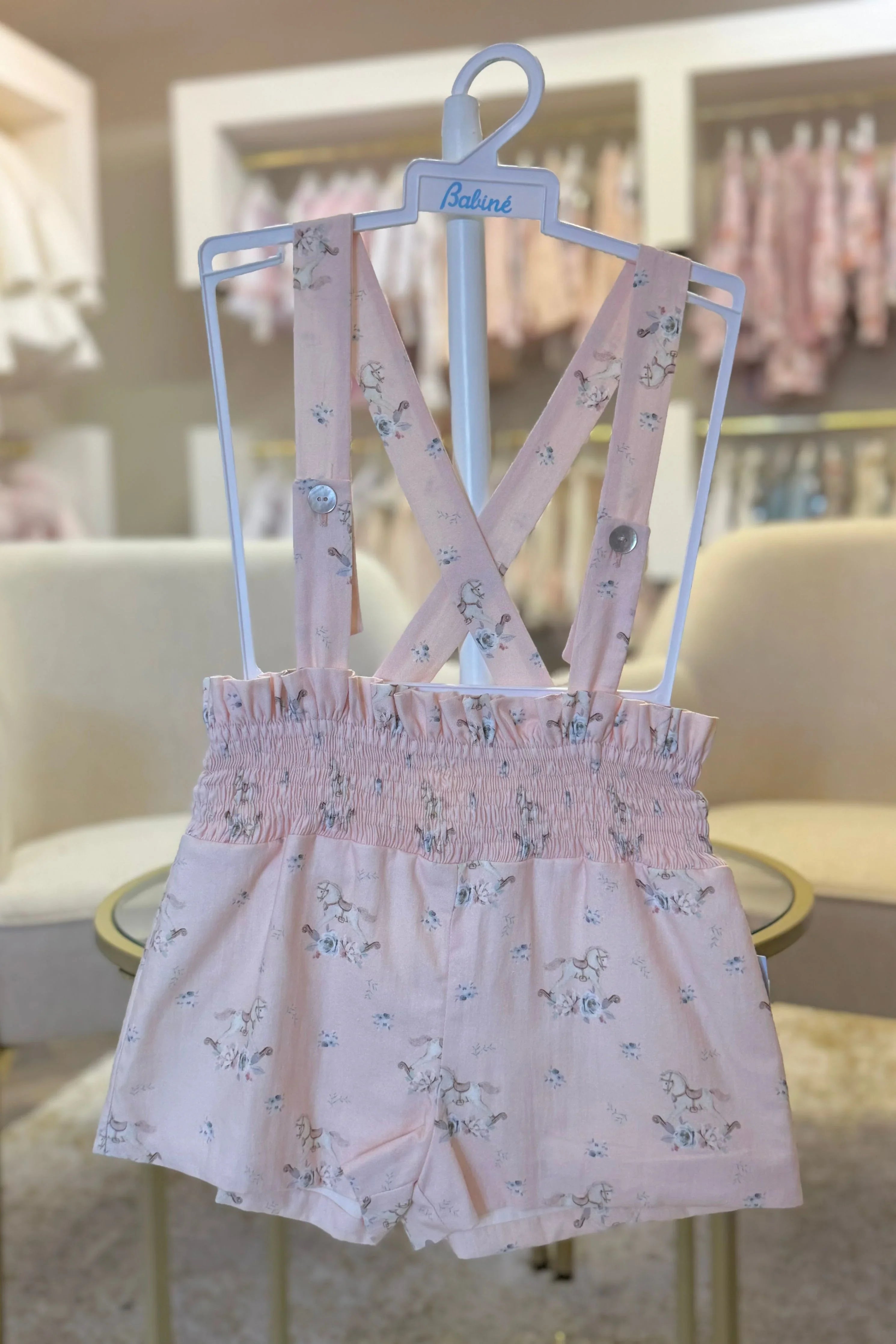 Pink girls' suspender shorts with floral and rocking horse print on white Babiné hanger