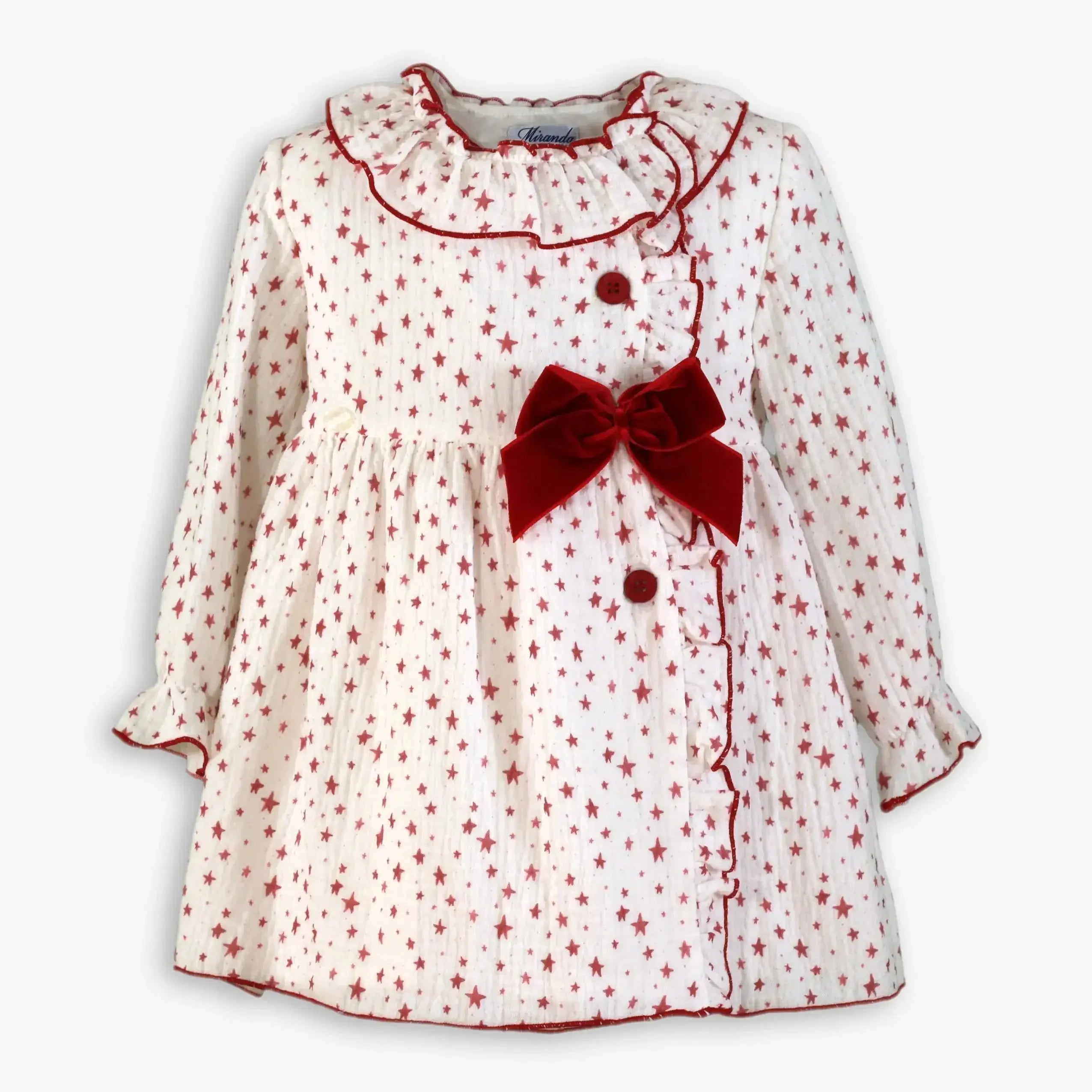 White baby dress with red star pattern, ruffled collar, red buttons, and large red velvet bow