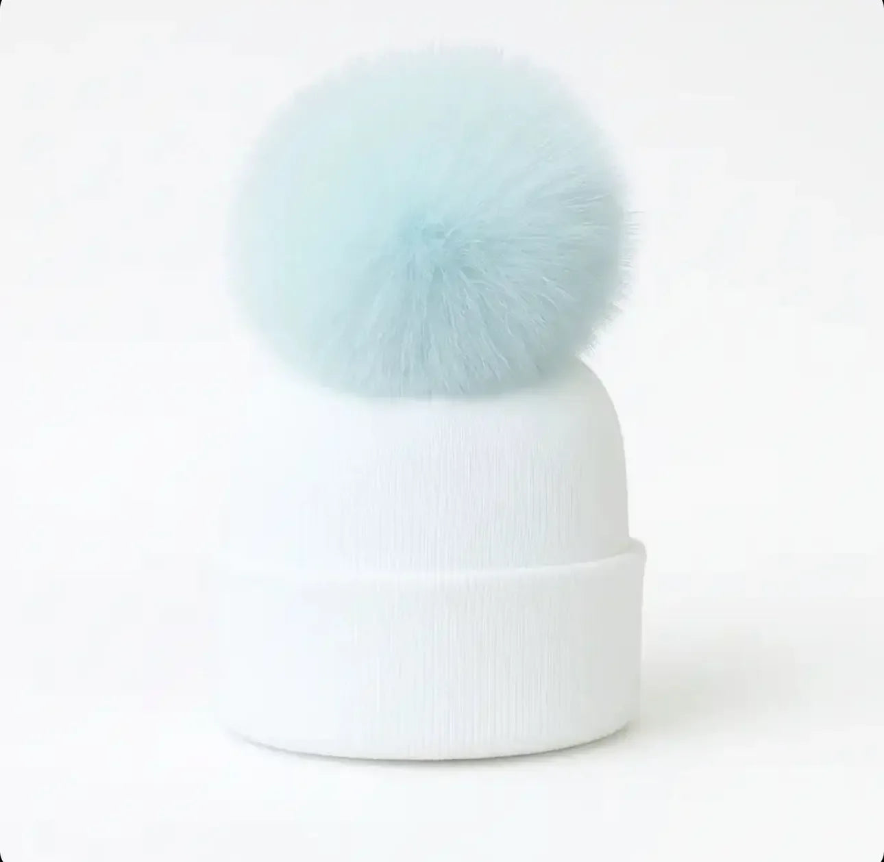 White knit winter beanie hat with large light blue fluffy pom pom on top