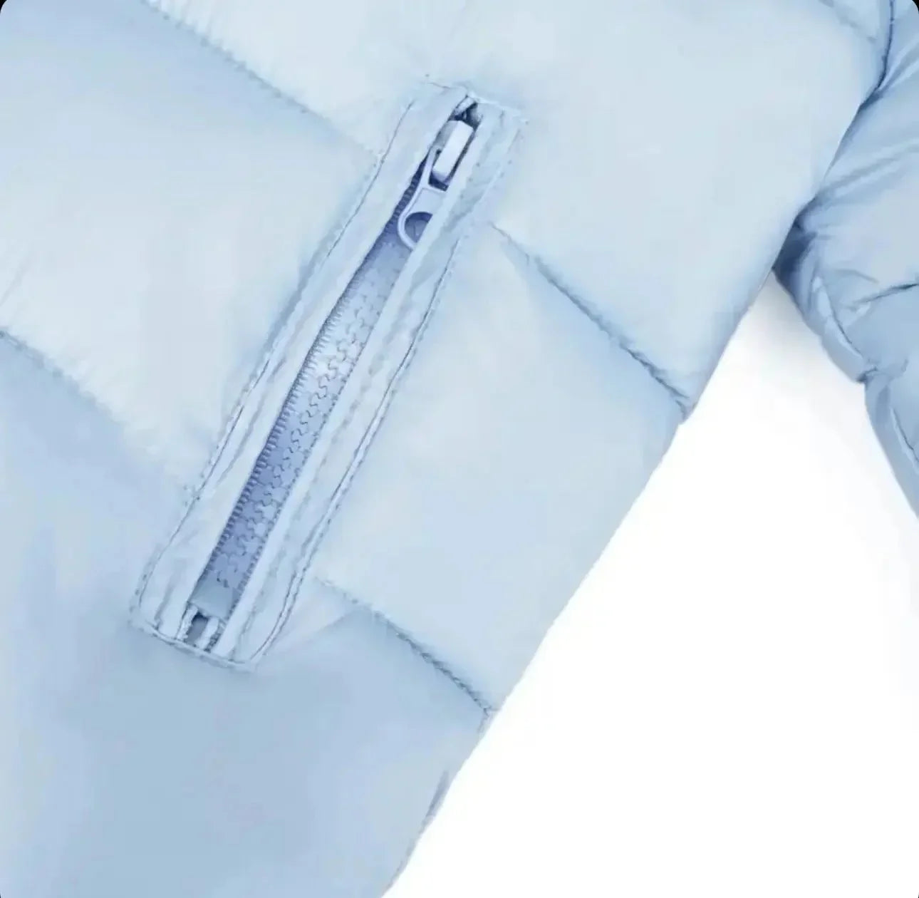 Close-up of light blue puffer jacket sleeve with visible zipper detail