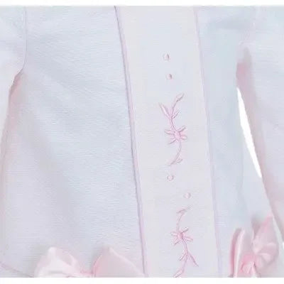 Close-up of white infant dress with pink floral embroidery and satin bow accents
