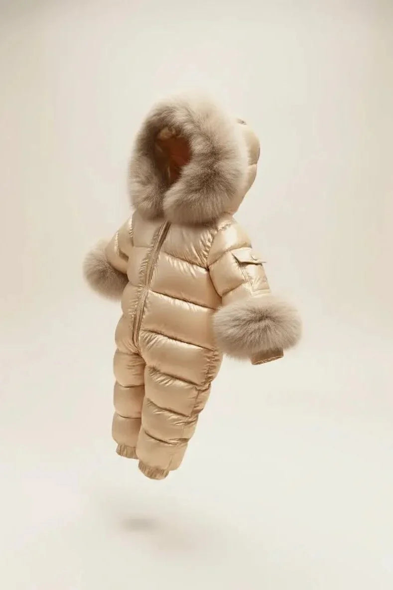 Beige shiny padded baby snowsuit with fur-trimmed hood and cuffs isolated on beige background