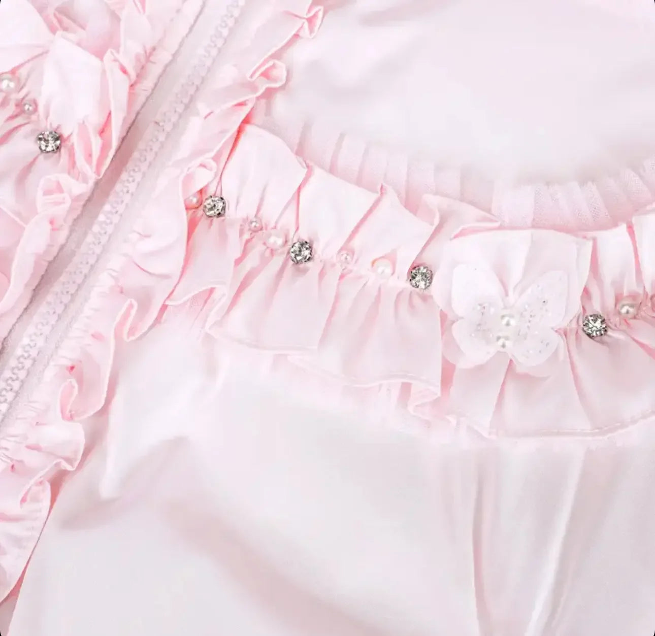 Pink baby dress detail with ruffles, rhinestones, pearls, and butterfly embellishment