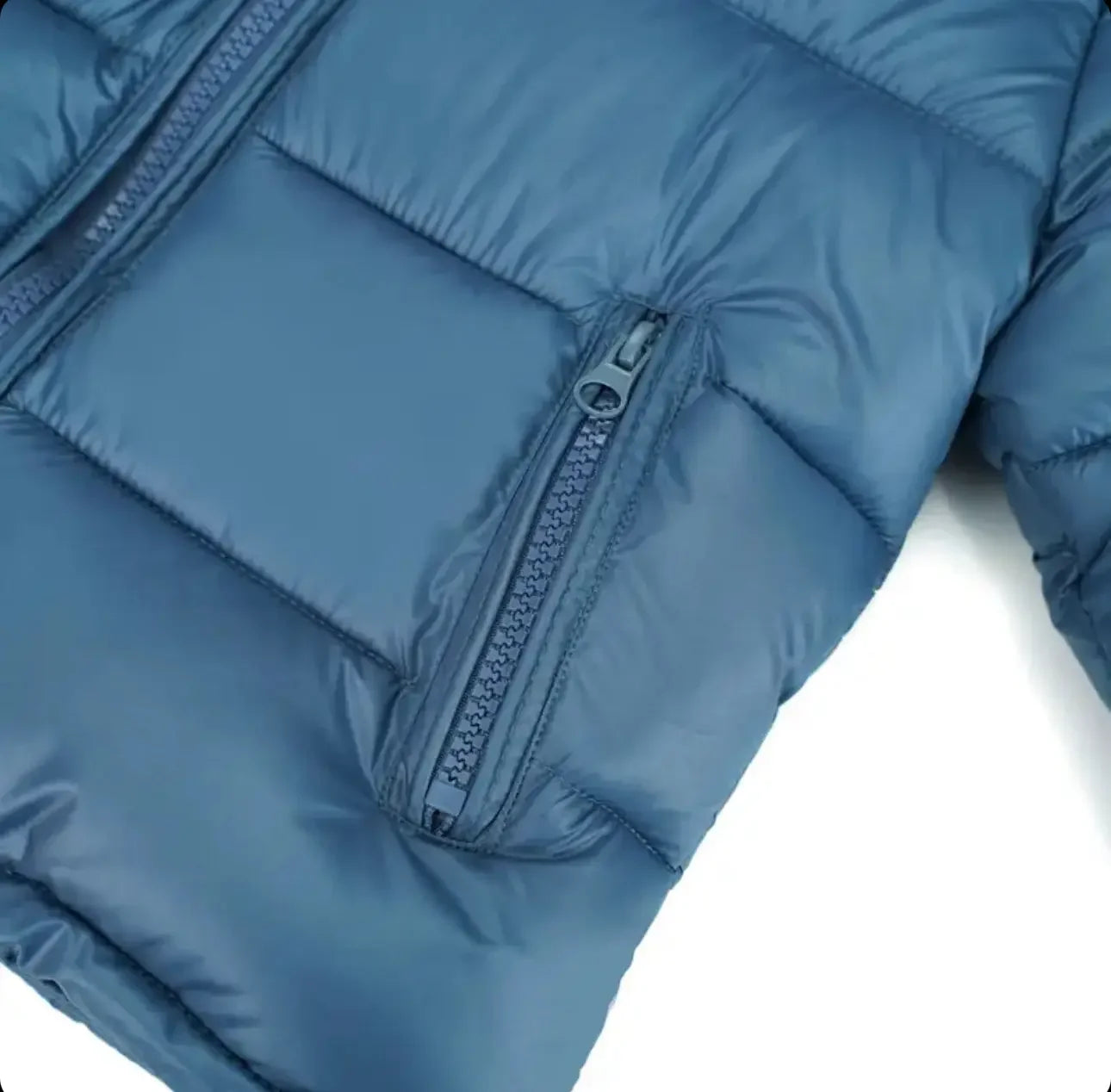 Close-up of blue puffer jacket with zippered pocket and quilted stitching detail