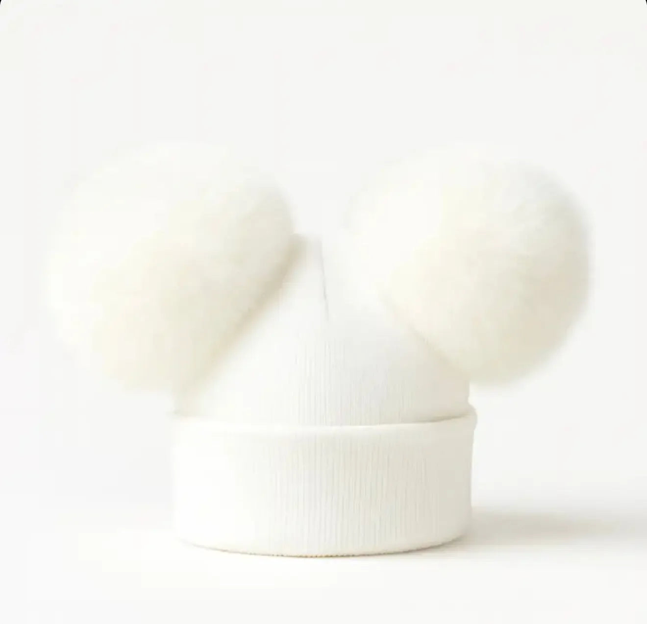 White knit beanie hat with two large fluffy pom-poms on a white background