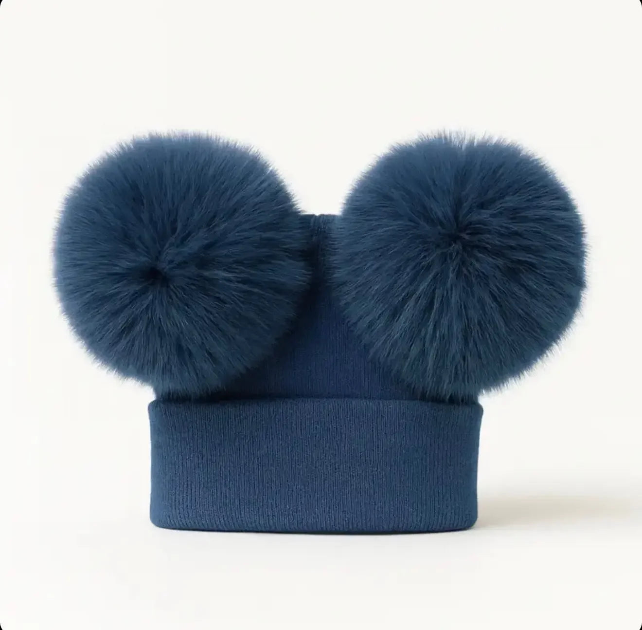 Navy blue knit beanie hat with two large fluffy pom-poms on top against white background