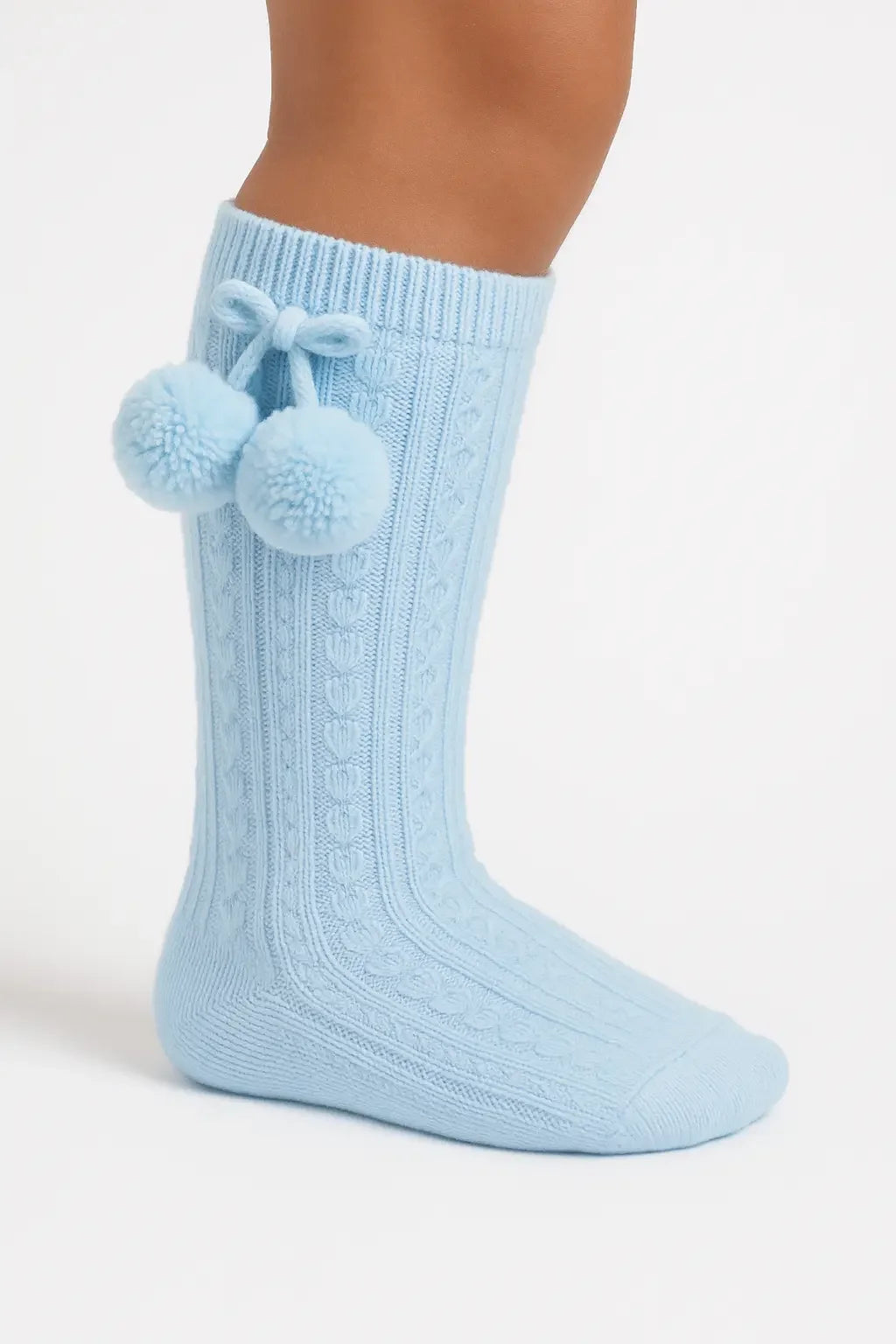 Light blue knitted knee-high sock with cable pattern and pom-pom tassels on the side