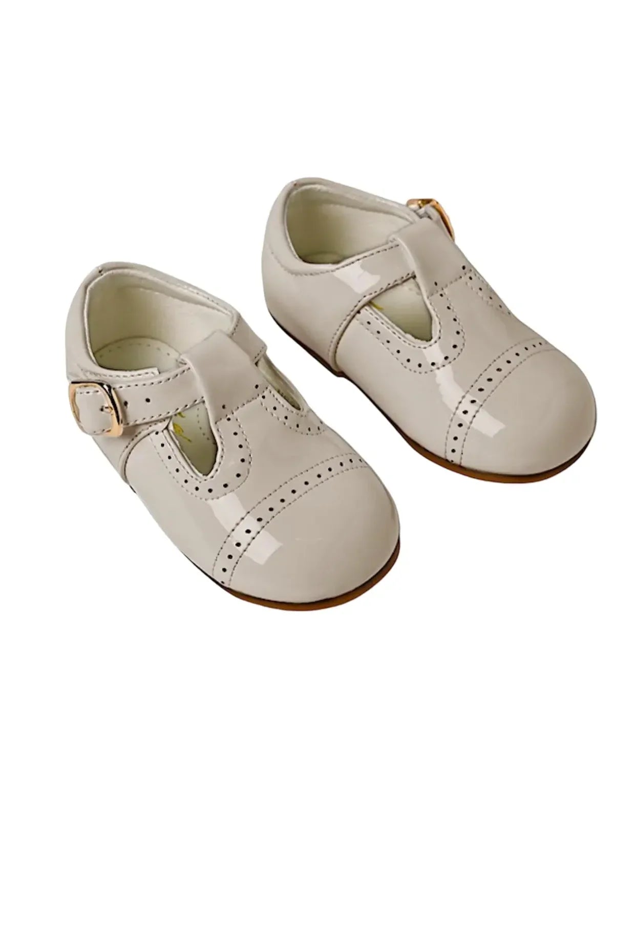 Pair of cream patent leather baby shoes with buckle straps and decorative perforations