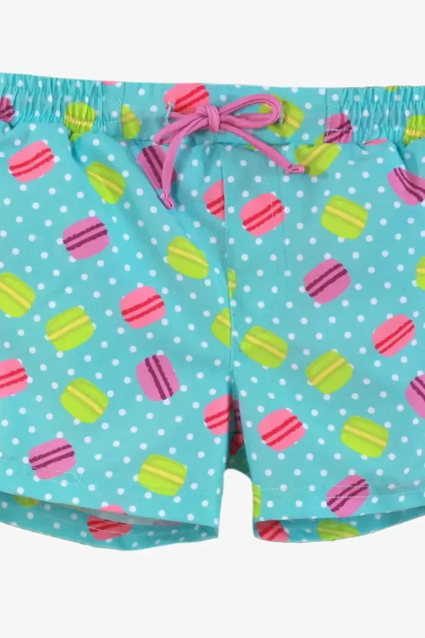 Blue swim shorts with white polka dots and colorful macaron print, pink drawstring at waist