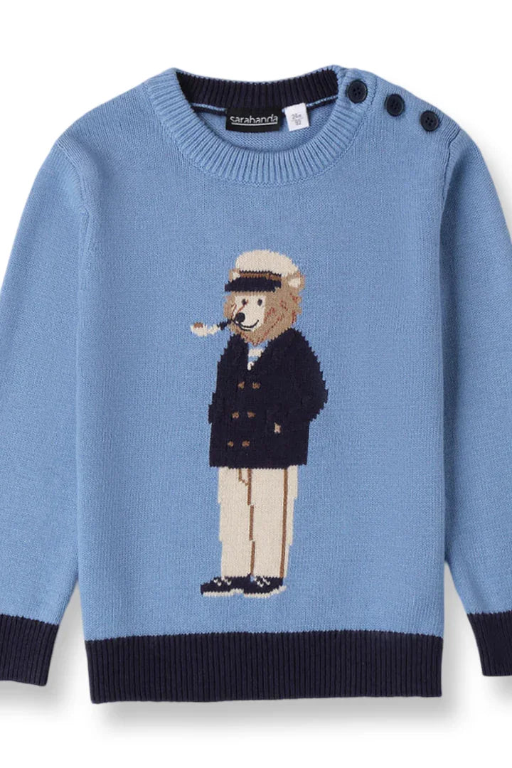 Blue knit sweater with navy cuffs and hem featuring a bear in a sailor outfit and buttons on the shoulder