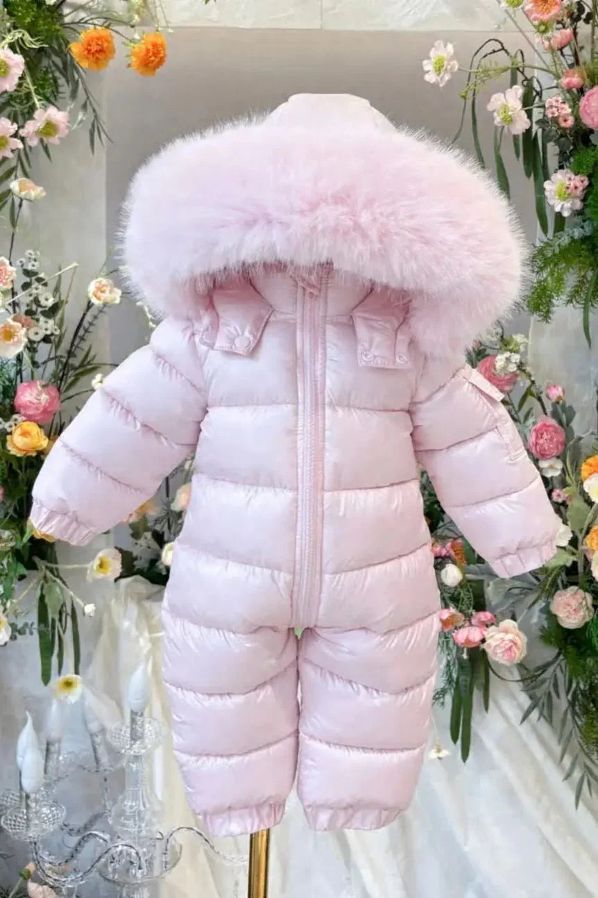 Pink baby snowsuit with fluffy hood displayed on a mannequin surrounded by colorful flowers