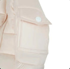 Close-up of beige puffer jacket sleeve with flap pocket and white snap button detail