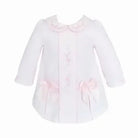 White baby dress with pink embroidery, scalloped collar, and two pink bows on front pockets
