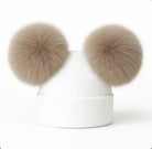 White ribbed knit winter beanie with two large beige faux fur pom poms