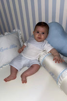 Baby boy sitting in white and blue nursery with Lucci Bleu embroidered pillows and soft cushions
