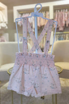 Pink girls' suspender shorts with floral and rocking horse print on white Babiné hanger