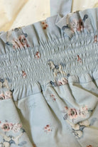 Close-up of light blue fabric with elastic smocking and floral pattern in soft pink and gray