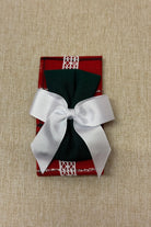 Red check fabric headband with green bow and white ribbon on beige background
