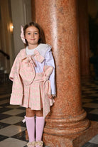 Young girl in pink houndstooth blazer and pleated skirt set with white blouse and knee-high pink socks