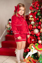 Young girl in red velvet blazer and shorts, festive Christmas decor with nutcrackers and ornaments
