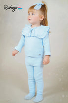 Toddler girl wearing a light blue knitted two-piece outfit with ruffles and a matching hair bow