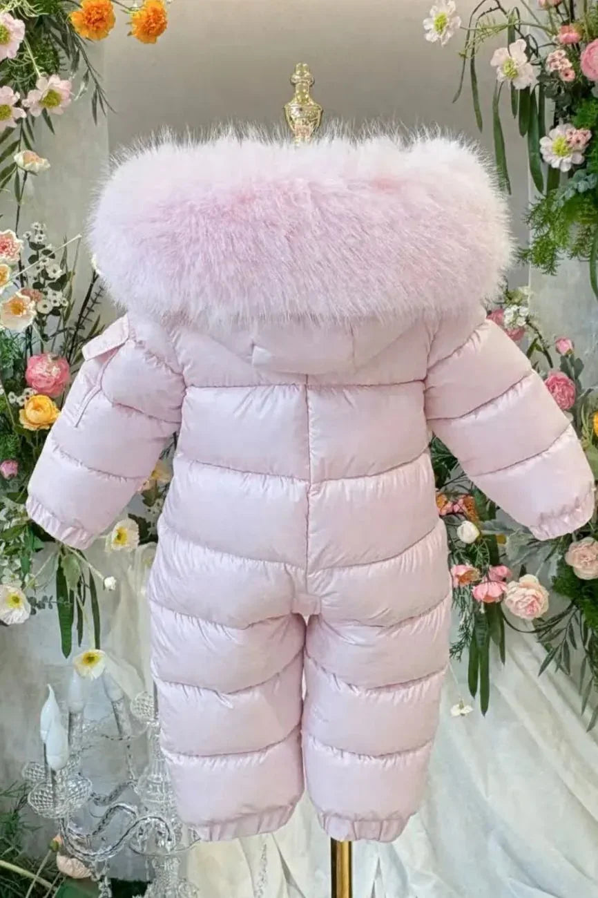Pink padded baby snowsuit with fluffy fur collar on gold mannequin surrounded by floral decor