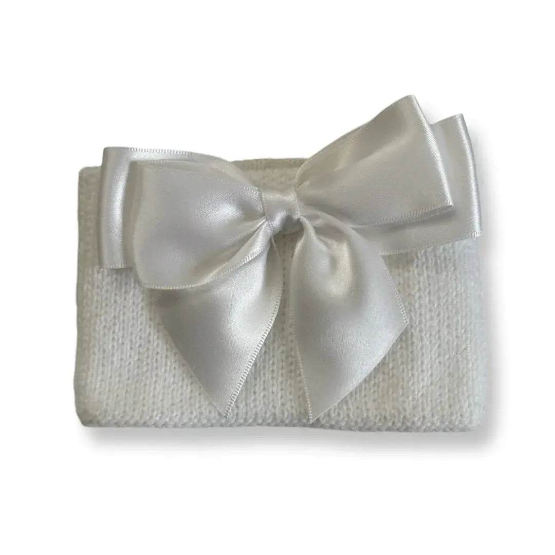 white knitted fabric folded with large satin white bow on top, minimalist gift wrap