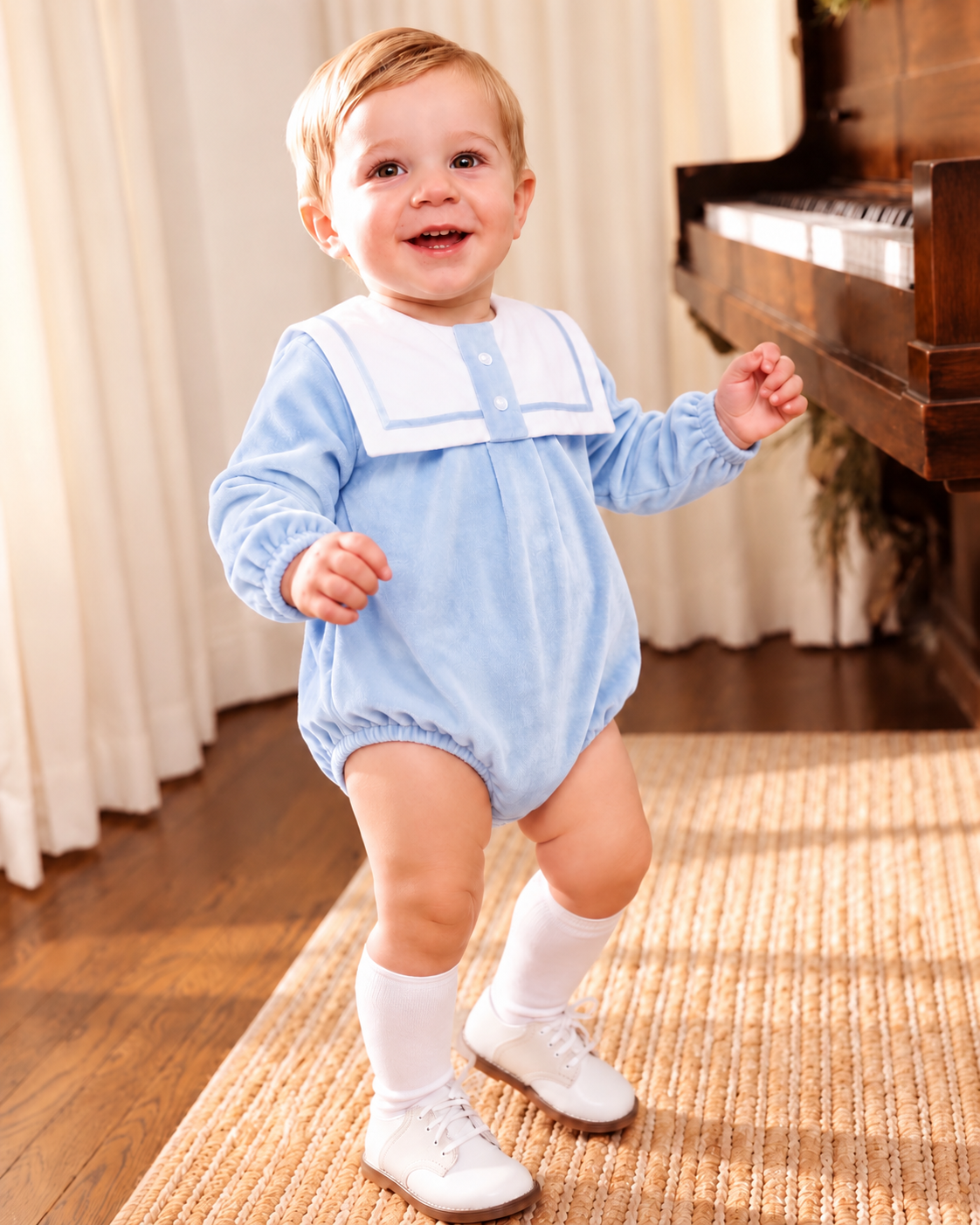 Baby boy wearing a baby blue velour sailor collar romper with white knee-high socks and traditional white shoes.