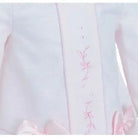 Close-up of white infant dress with pink floral embroidery and satin bow accents