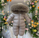 Beige baby snowsuit with large fur-trimmed hood displayed against floral background