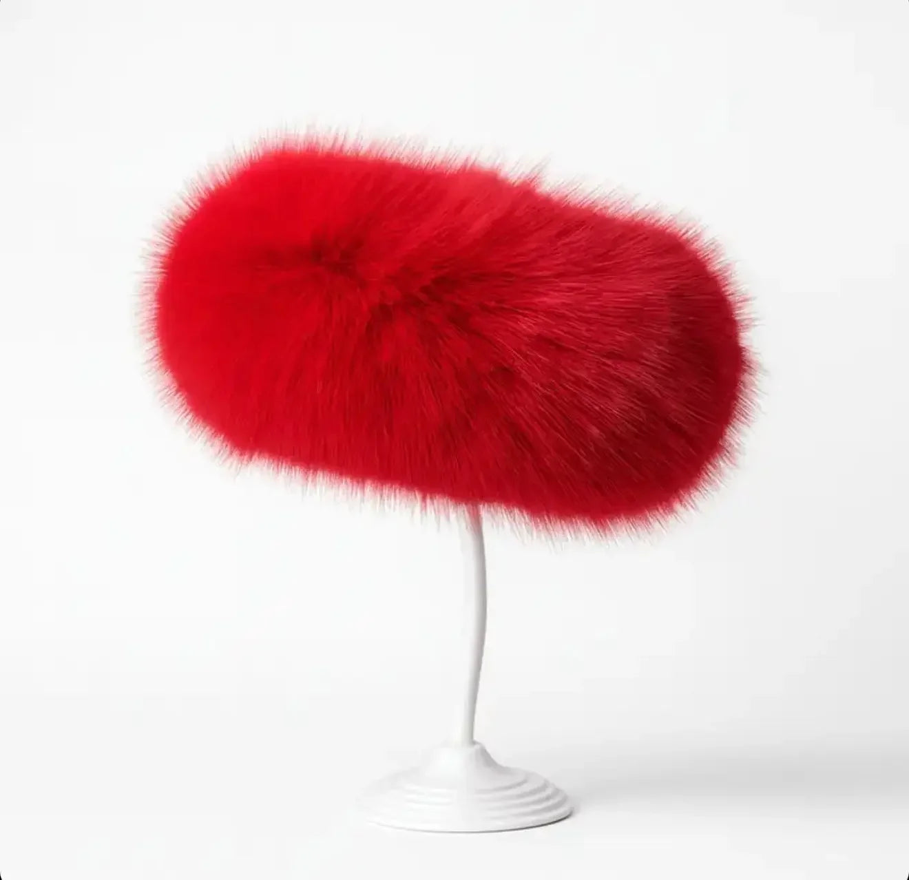 Red fur-covered modern sculptural object on white curved pedestal stand