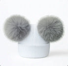 White ribbed knit beanie with two large gray faux fur pom poms on top