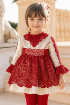 Smiling young girl wearing red lace dress with long sleeves and matching hair accessory