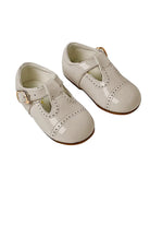 Pair of cream patent leather baby shoes with buckle straps and decorative perforations