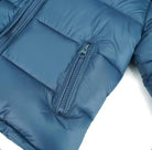 Close-up of blue puffer jacket with zippered pocket and quilted stitching detail