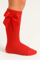 Red knitted knee-high sock with cable pattern and large satin bow on side