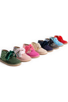 Line of colorful glitter toddler boots with velvet bows on white background