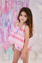 Young girl modeling pink and lilac zig-zag pattern baby girls' swim top and knickers in pastel party setting