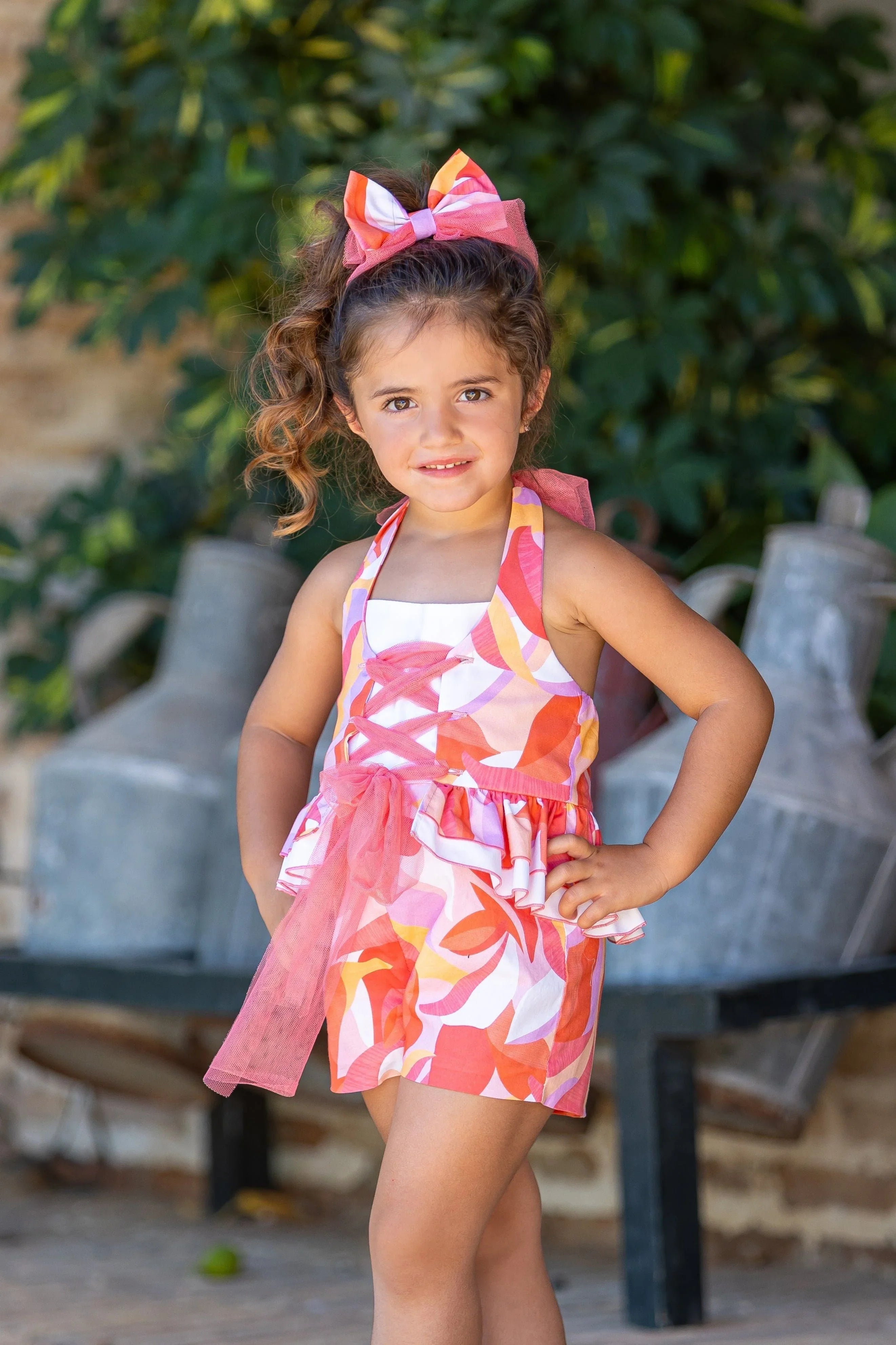 Young girl in colorful orange and pink floral halter top and shorts set posing outdoors