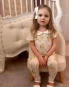 Little girl wearing vintage lemon print loungewear set sitting on a plush chair in cozy room