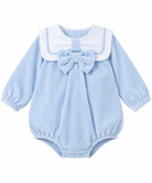 Baby girls’ baby blue velour romper with white sailor collar, blue piping, oversized matching bow and long sleeves on a white background.